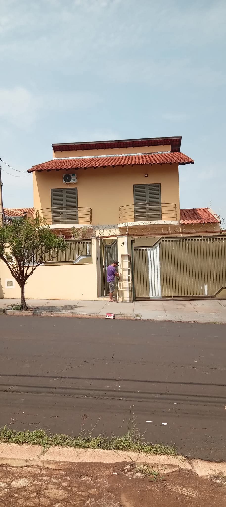 Fachada de casa residencial bege de dois andares com pintura em andamento