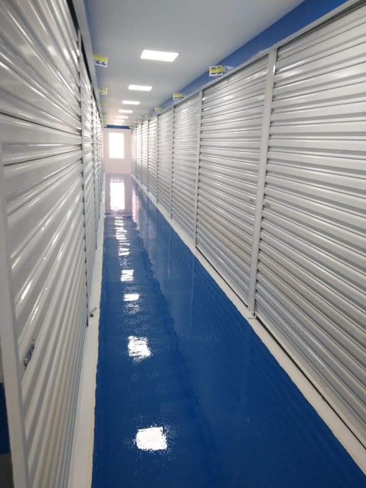 Corredor industrial com piso azul de epóxi brilhante e portas de aço
