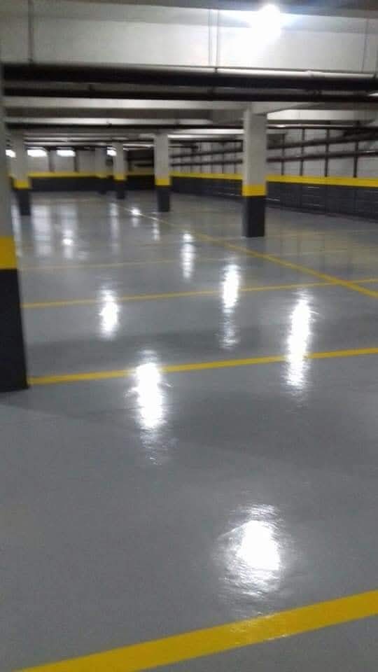 Garagem com piso cinza brilhante e faixas amarelas de demarcação